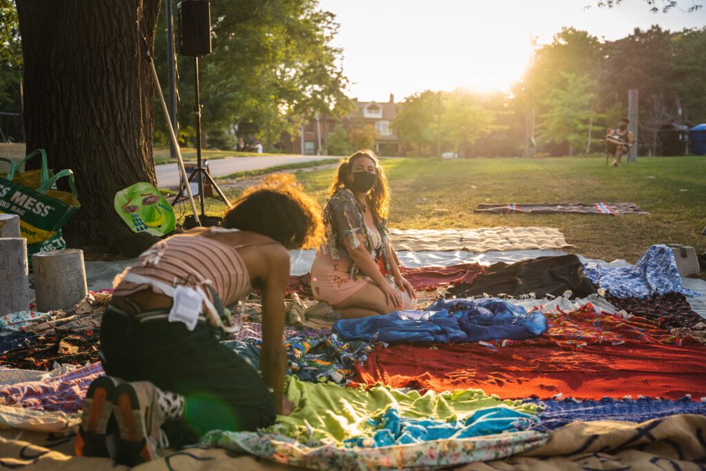 Production still of two actors on a quilt under trees at dusk