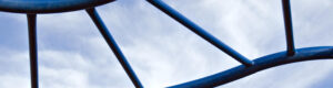 A sunny blue sky with light clouds. A macro photo through blue twisting monkey bars.